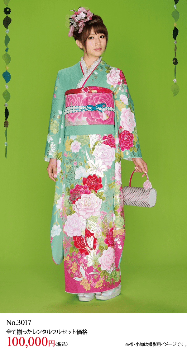色鮮やかな花柄の着物を着た女性が、小さなハンドバッグを持って緑の背景に立っています。.