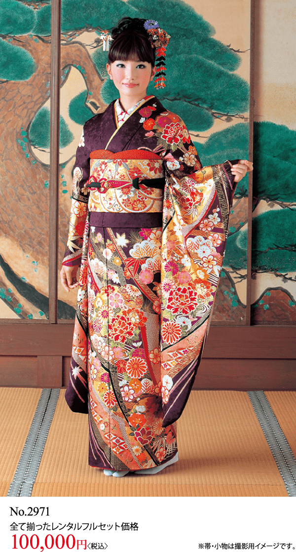 華やかな花柄の着物を着た人が、樹木を描いた衝立の前の畳の上に立っています。.