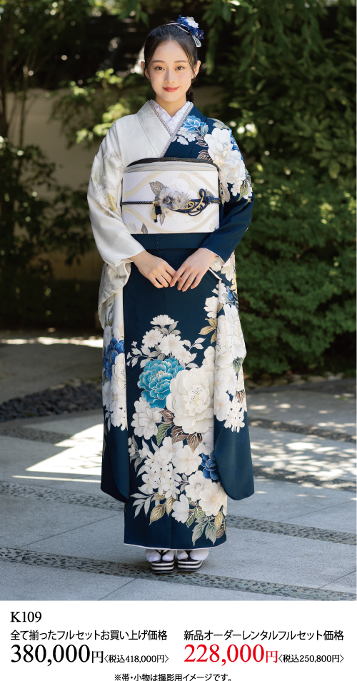 花柄の紺と白の伝統的な着物を着て、飾り帯を締めた若い女性が屋外に立っている。この衣装のレンタルと購入のオプションを強調するために、日本の価格とテキストが下に表示されます。.